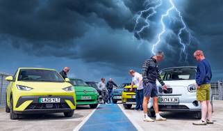 Auto Express team standing with a selection of EVs underneath a lightning storm